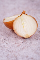 A halved onion on a white stone surface background.