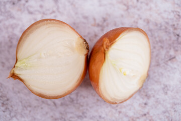 A halved onion on a white stone surface background.