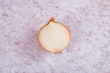 A halved onion on a white stone surface background.