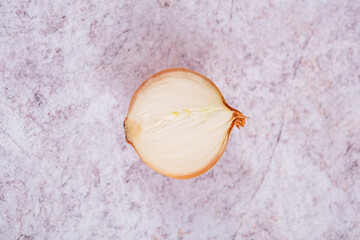 A halved onion on a white stone surface background.
