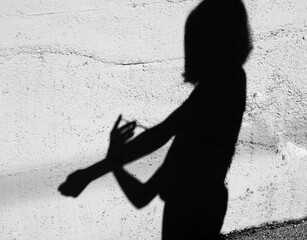 Shadow on the wall of a drug addict boy during injection with syringe in the city suburb