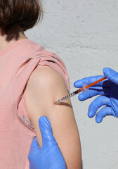 vaccinating young schoolgirl with syringe with mRna vaccine and arm without seeing face and blue latex gloves - obrazy, fototapety, plakaty