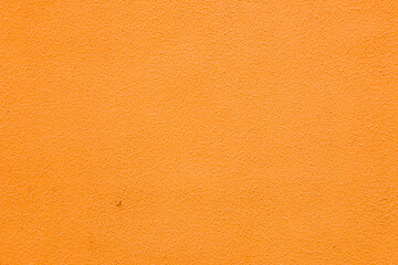 A wall with worn orange plaster.