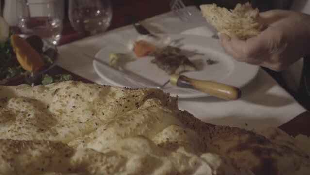 A man who tastes the horizontally cooked kebab typical of Turkish food culture and the products served with it at the dinner table.