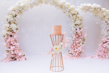pink gift box on the metal decorated table by the wedding ceremony arch with pink and white flowers.