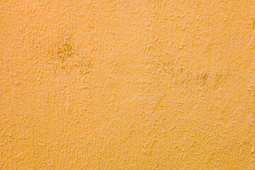 A wall with worn orange plaster.
