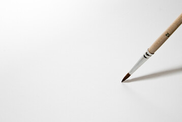 a thin needle brush writes on the blank white paper