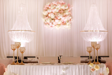 festive wedding table decoration with crystal chandeliers, golden candlesticks, candles and white pink flowers . stylish wedding day.