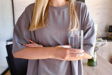 Girl is holding a transparent glass with drinking clean water. Healthy lifestyle concept, skin care. Glass with water in hands close-up. Healthy food. Body water balance for health
