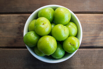 Fototapeta na wymiar Bowl of fresh and green plums.