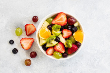 Healthy fresh fruit salad in bowl on gray concrete background. top view.  - Powered by Adobe