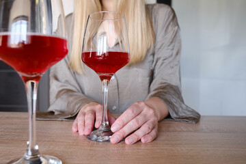 A glass of red wine in the hands of a girl relaxing in a restaurant. Tasting of alcoholic beverages. Summer rest. Romantic evening aperitif. Close-up of a glass of wine. Enjoy the moment 

