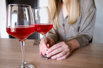 A glass of red wine in the hands of a girl relaxing in a restaurant. Tasting of alcoholic beverages. Summer rest. Romantic evening aperitif. Close-up of a glass of wine. Enjoy the moment 