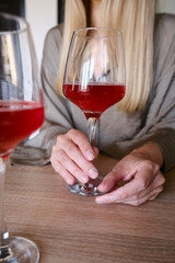 A glass of red wine in the hands of a girl relaxing in a restaurant. Tasting of alcoholic beverages. Summer rest. Romantic evening aperitif. Close-up of a glass of wine. Enjoy the moment 
