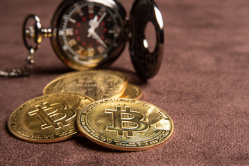 Bitcoin, bitcoin coins and a vintage pocket watch placed on a brown leather background, selective focus.