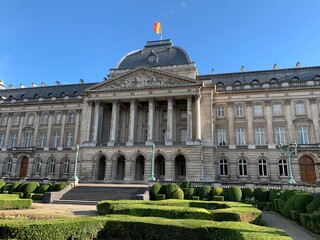 Obraz premium Front facade of The Royal Palace of Brussels. It is is the official palace of the Belgian Royal family in the city centre. Belgian flag is waiving on top of the building. Bruxelles, Belgium