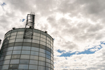 silver silos on agro manufacturing plant for processing drying cleaning and storage of agricultural products, flour, cereals and grain. Large iron barrels of grain. Granary elevator
