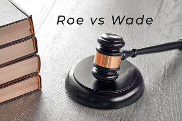 Roe versus Wade text. Old books and law hammer on wooden table.