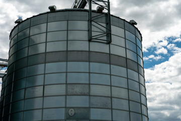 silver silos on agro manufacturing plant for processing drying cleaning and storage of agricultural products, flour, cereals and grain. Large iron barrels of grain. Granary elevator