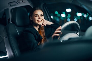 horizontal photo of a cute, relaxed woman sitting behind the wheel of a car smiling pleasantly in a relaxed state. Photo on the topic of safe driving