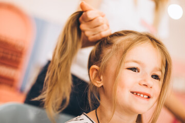 Stylish little girl in a beauty salon for children where she made a beautiful hairstyle