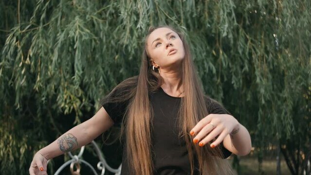 Portrait of young woman listening music and dancing in green city park