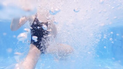 Girl with swimsuit swimming on a blue water pool with underwater rising bubbles, slow motion