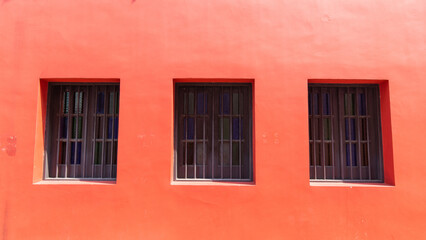 Three windows on a red wall.