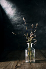 Glass bottle with dry lavender branches on a blurred background