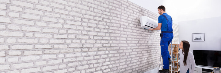 Male Technician Fixing Air Conditioner On Wall