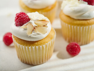 Close-up. Appetizing muffins with cream, decorated with raspberries and almonds. Delicious light dessert. Birthday, wedding, romantic date. Advertising, banner, invitation.
