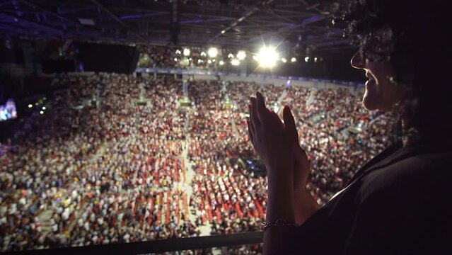 Young hispanic woman give a standing ovation applauding to the performers on stage