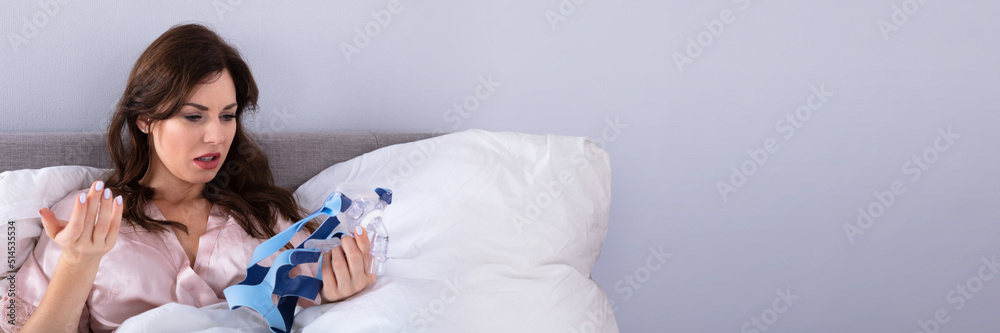 Wall mural worried woman looking at cpap mask