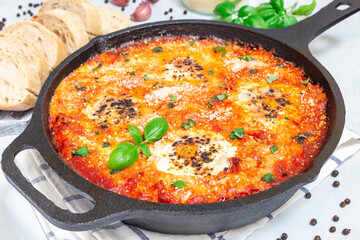 Shakshuka with eggs, Italian sausage, tomato sauce, in cast iron pan, horizontal