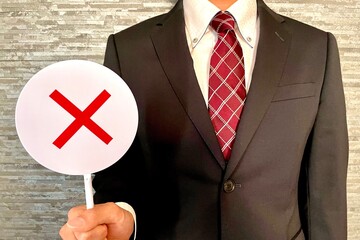 バツのプラカードを持つサラリーマン