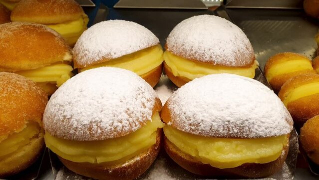 Several brazilian cream donuts in a brazilian bakery showcase.