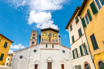 Fototapeta na wymiar The facade and bell tower of the San Frediano Basilica, a Romanesque church with golden mosaic facade inside the walled medieval town of Lucca, Italy.
