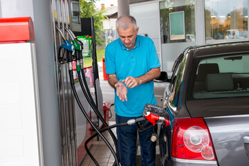 Mature man pouring petrol into tank of his vehicle on filling station. Travel,transportation and holiday