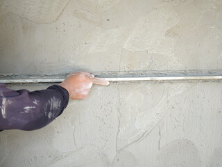 Plasterer using screeder smoothing putty plaster mortar on wall. house building concept.