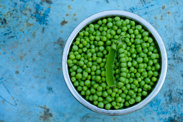 A bowl of green peas on a blue rusty background. Copy space.