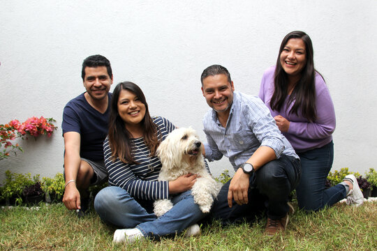 Latino Family Pose With Their Adopted White Furry Dog ​​making Up A Diverse Family With No Children
