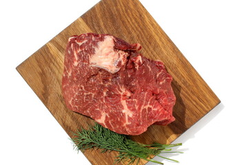 A piece of marbled meat lies on a wooden board.