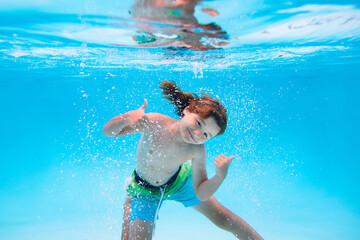 Summer kids in water in pool underwater. Child swimming underwater in swimming pool. Funny kids boy play and swim in the sea water.