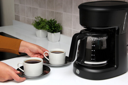 Woman's hands serve coffee prepared in a coffee maker to start the day with the benefits of antioxidants, protects against cancer, fights Alzheimer's and Parkinson's
