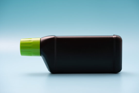 Black Plastic Bottle With A Green Cap On A Blue Background