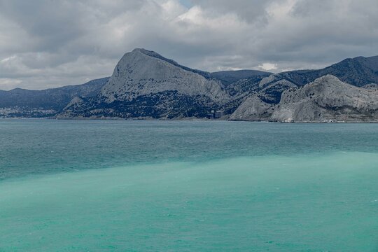 emerald sea against the background of mountains and sky with dark clouds