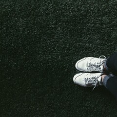 White sneaker shoe on dark green grass