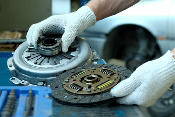 Maintenance of a passenger car in a service center. A clutch kit is in the hands of an auto...