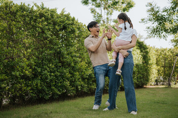 Fototapeta premium Family having fun time at home. Asian family with little kids daughter playing together in house backyard outside. Happy family time.