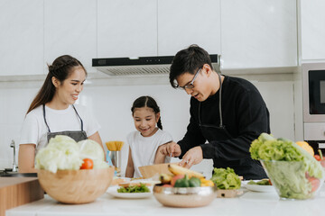 Asian family have fun cooking at home together. Happy dad and mom with little daughter cooking together in kitchen house. Family activities concept.
